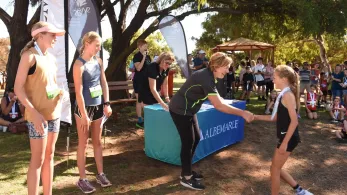 Community event with several young woman and Albemarle representative shaking hands with winner of race.