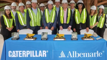 Workers in front of table with Caterpillar and Albemarle logos. 