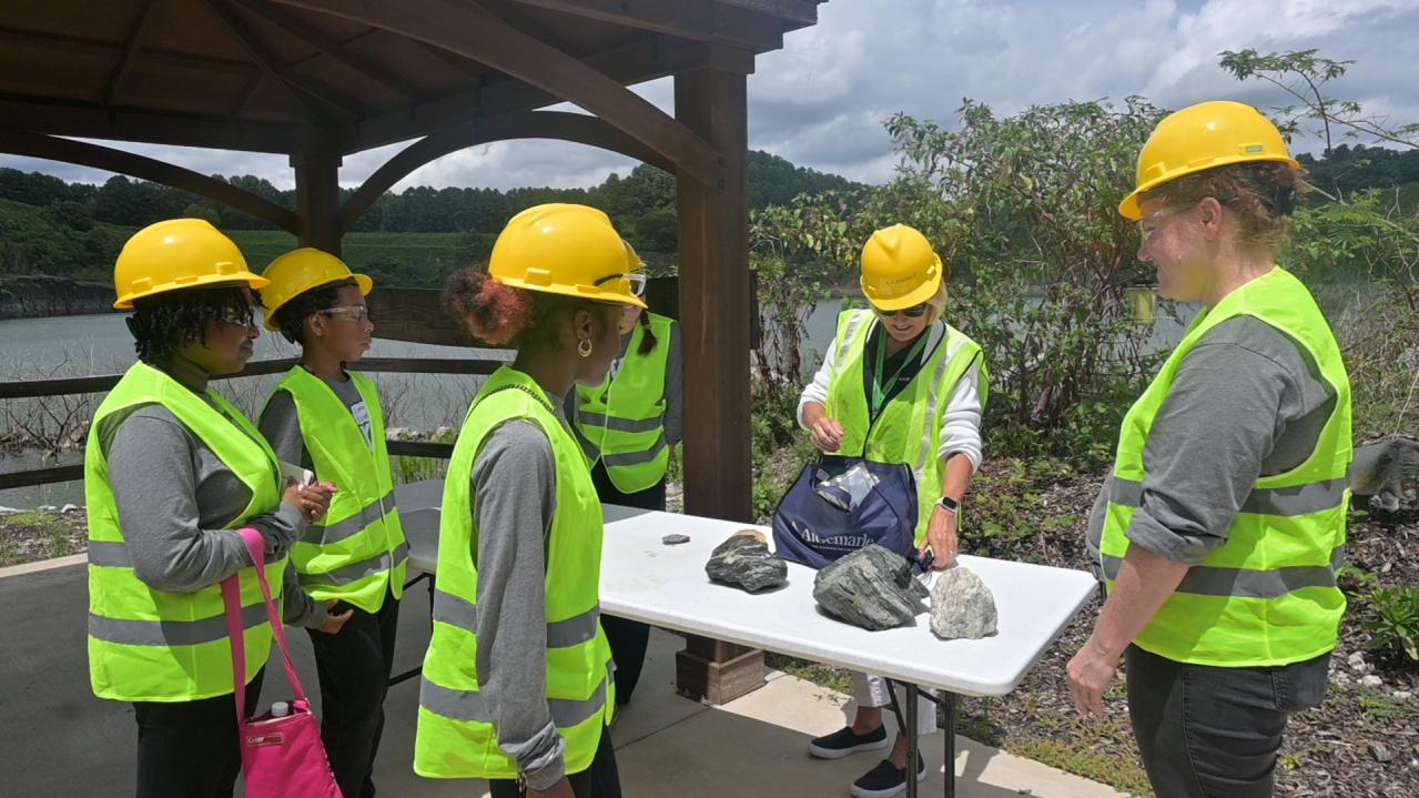 students in hard hats outside learning