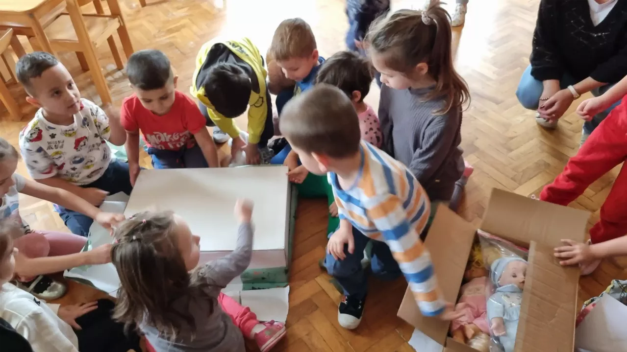 Children on floor huddled around small table.