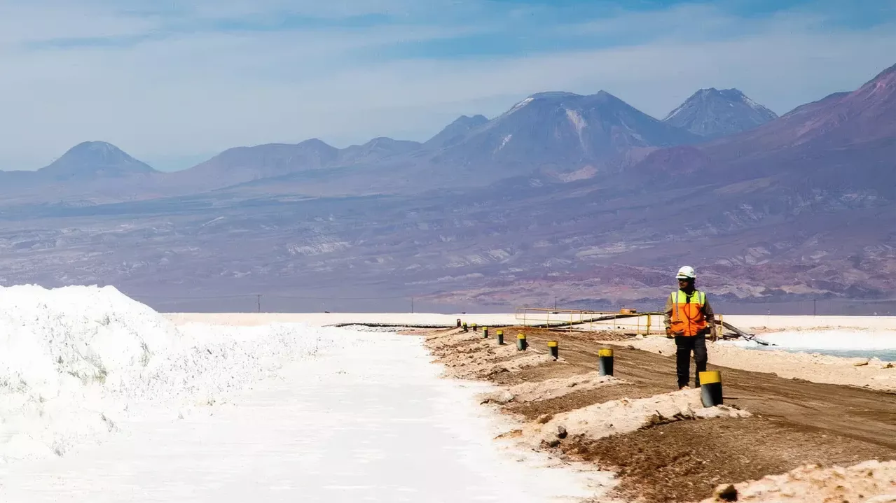 Worker on a barrier in the Salar with piles of lithium salts. 