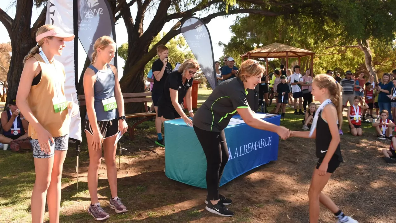 Community event with several young woman and Albemarle representative shaking hands with winner of race.