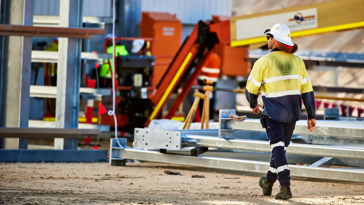 Man in hardhat walking on construction site.