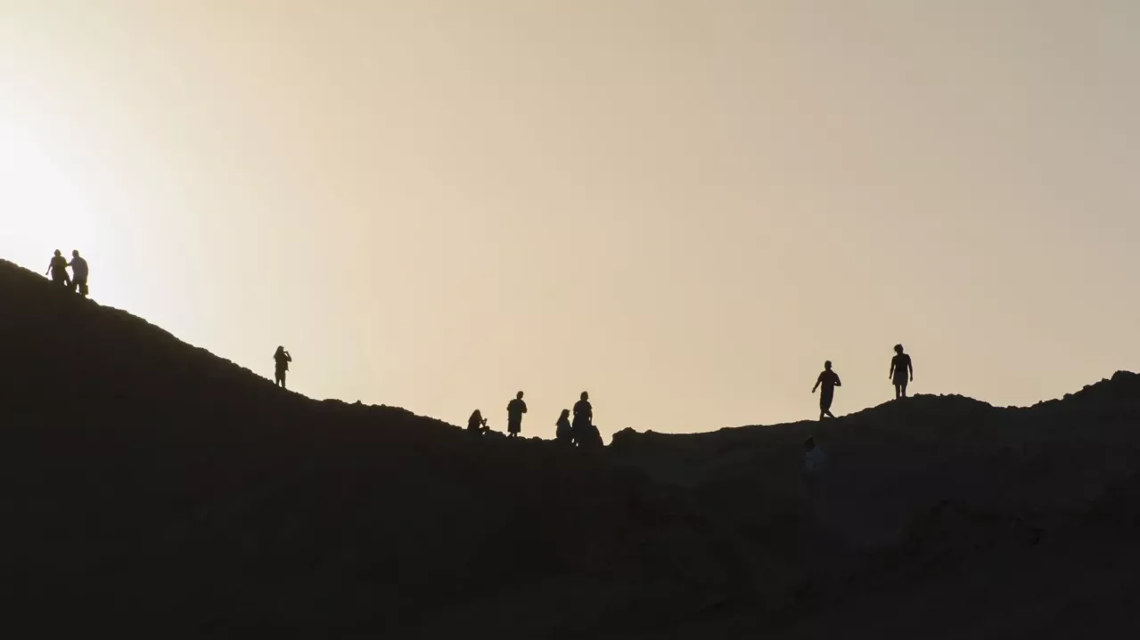 People on a hill silhouetted against the sky.