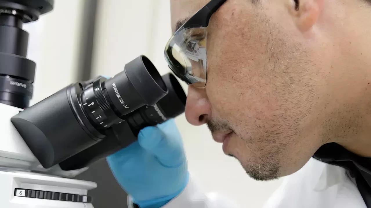 Close up of technician at microscope.