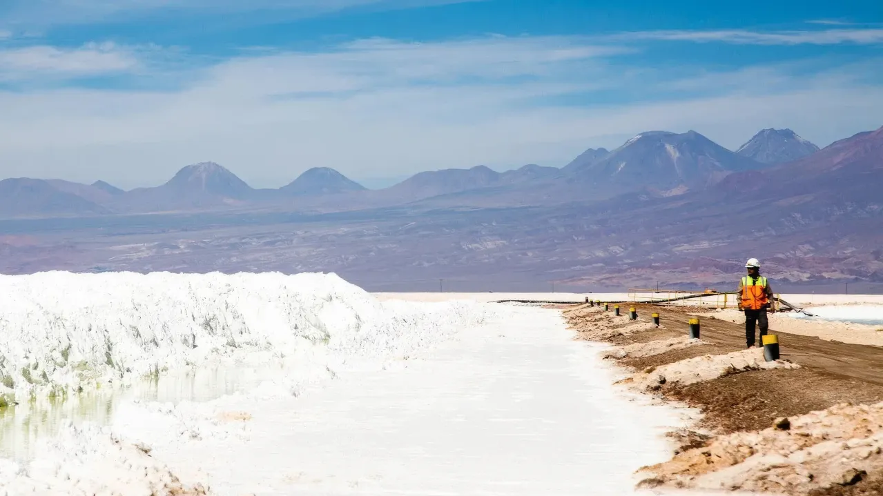 Worker on a barrier in the Salar with piles of lithium salts. 
