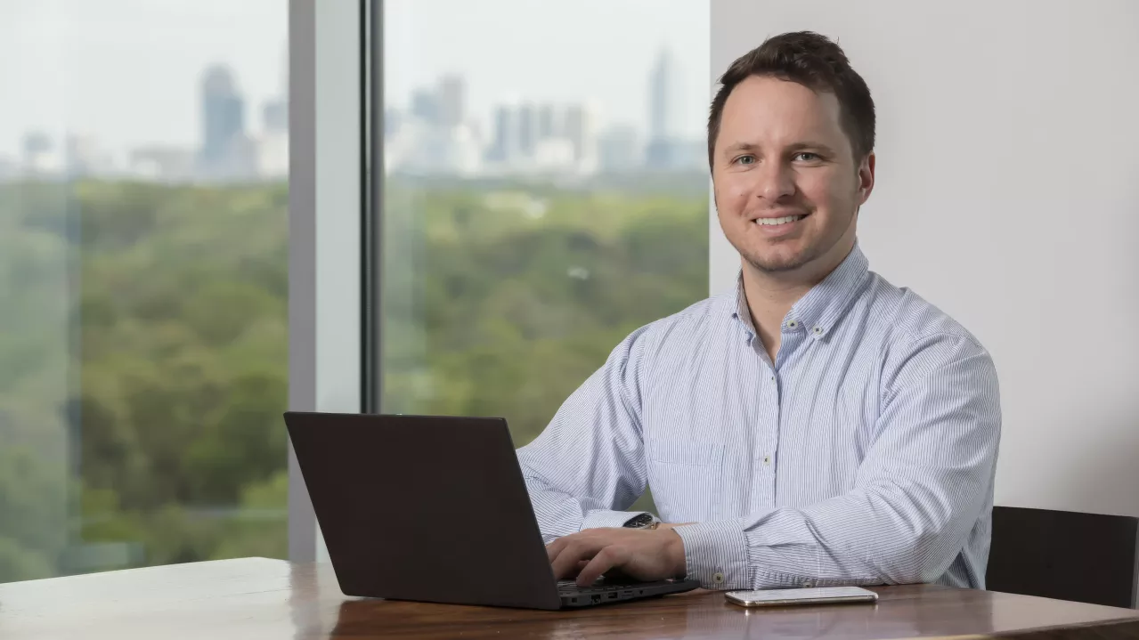 Man smiling at camera with open laptop.