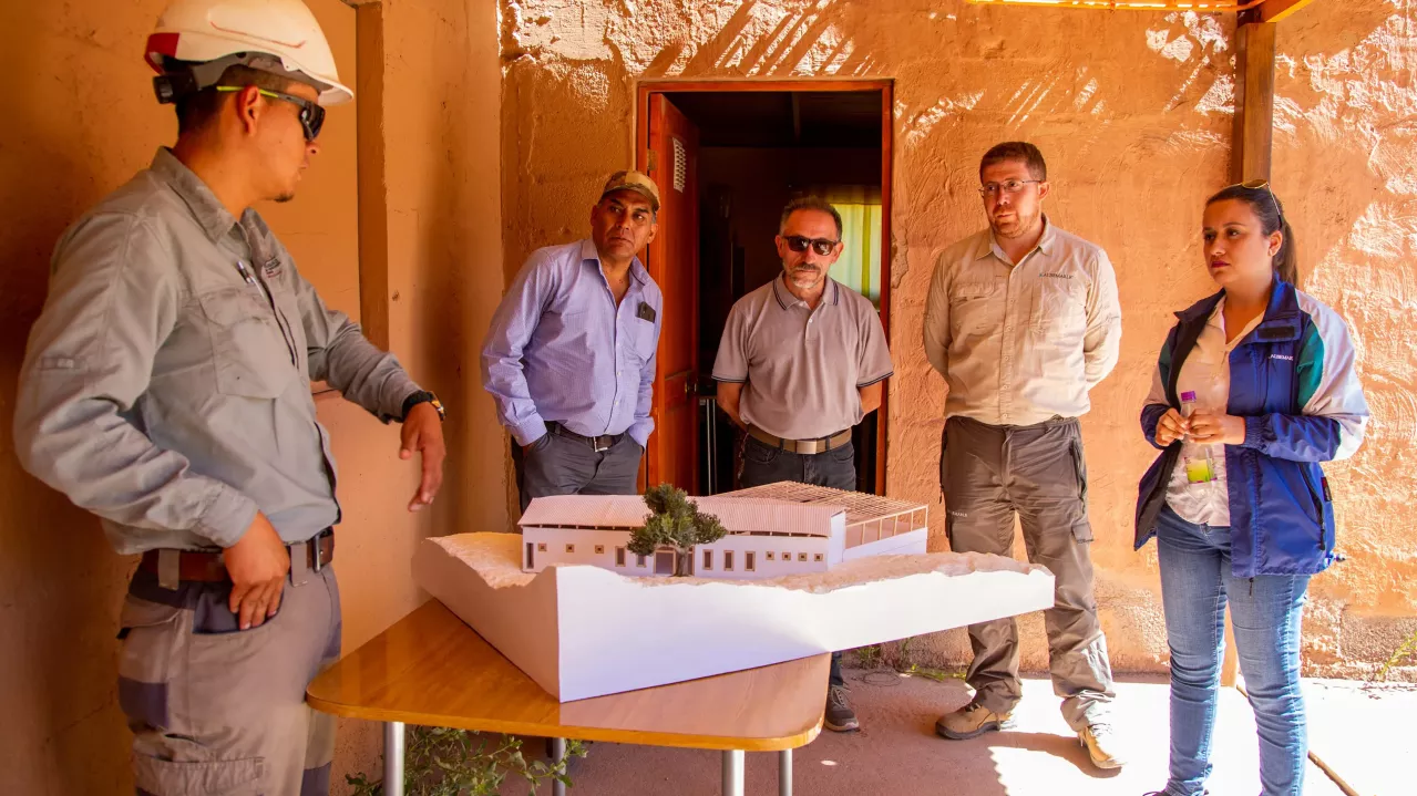 Leader and community representatives gathered around an architectural model of a site.