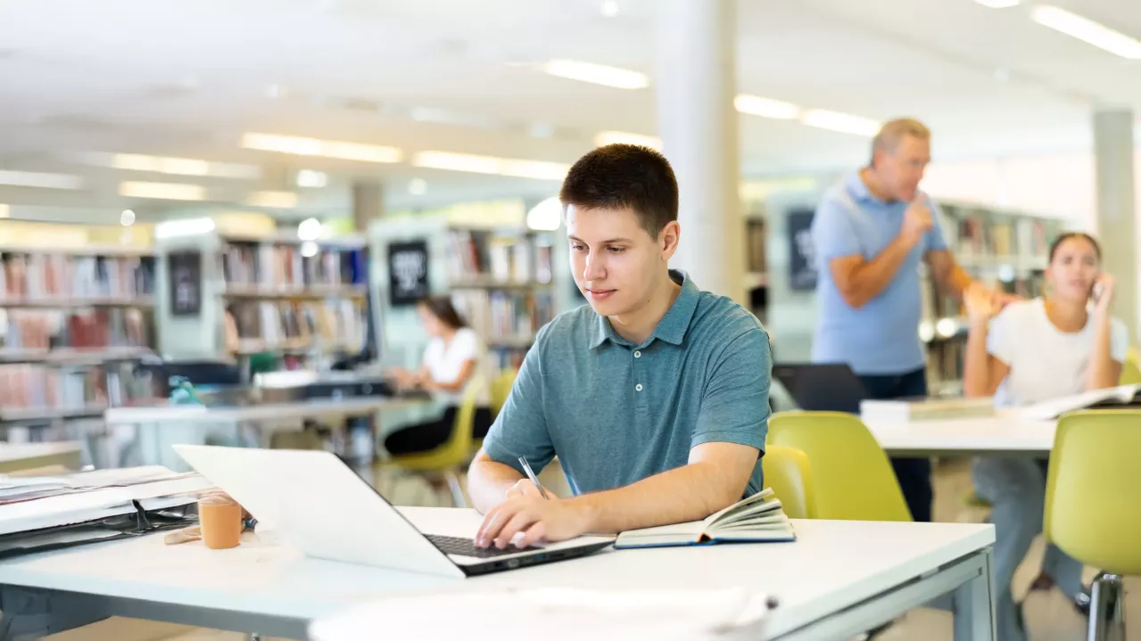 Young man on laptop in library.