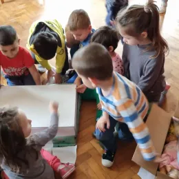 Children on floor huddled around small table.