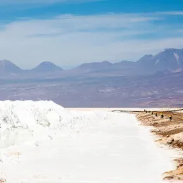 Worker on a barrier in the Salar with piles of lithium salts. 