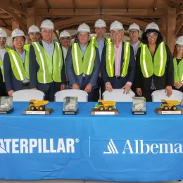 Workers in front of table with Caterpillar and Albemarle logos. 