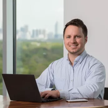 Man smiling at camera with open laptop.