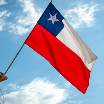 Chile National Flag waving on pole against sunny blue sky.