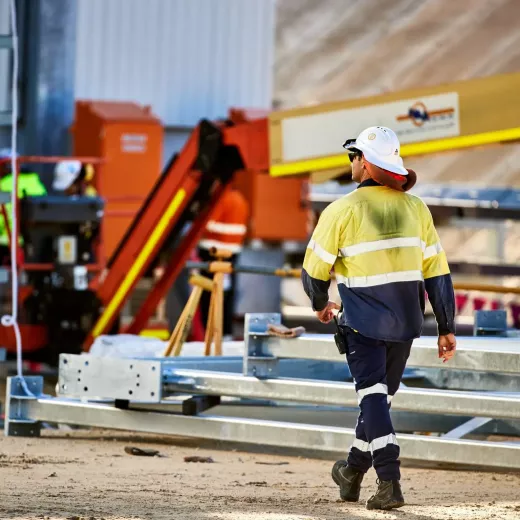 Man in hardhat walking on construction site.