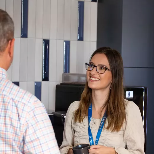 Young woman smiling and speaking to fellow coworker.