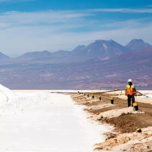 Worker on a barrier in the Salar with piles of lithium salts. 