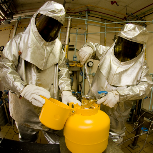 Image of individuals in protective gear opening a chemical container