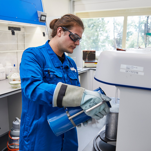 Image of male chemist pouring material while wearing protective gear