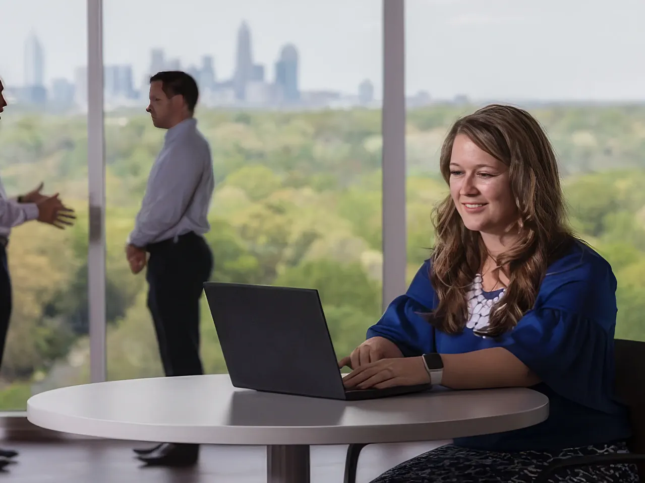 Woman working on laptop at small desk.